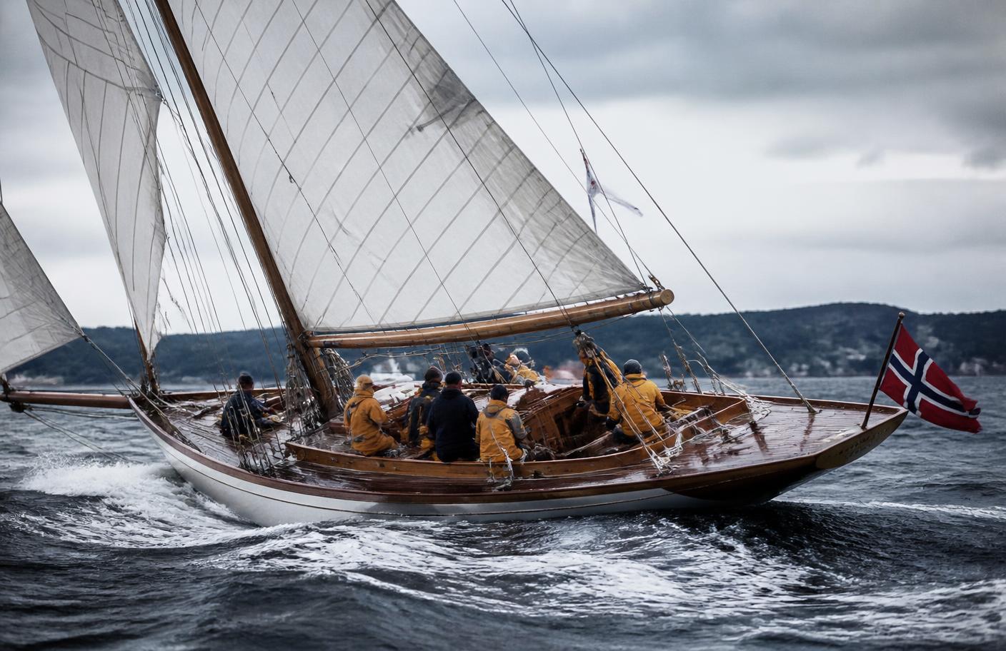 A classic wooden racing yacht under sail on the Oslofjord flying the Norwegian flag
